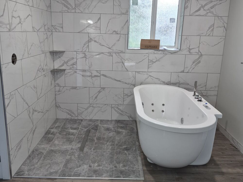 The finished bathroom with a tiled walk-in shower and soaker tub