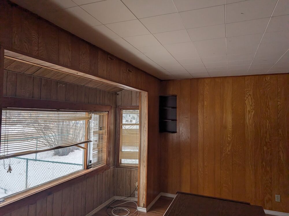 A room with original dark wood panelling and drop ceiling