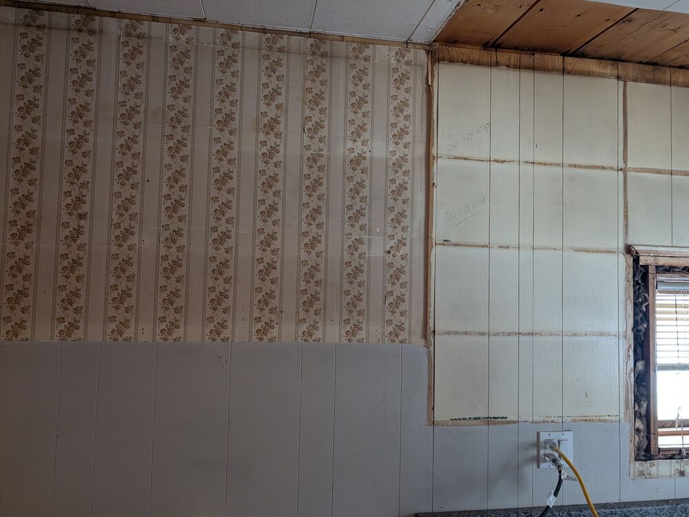 Original patterned wallpaper being stripped from a bedroom wall